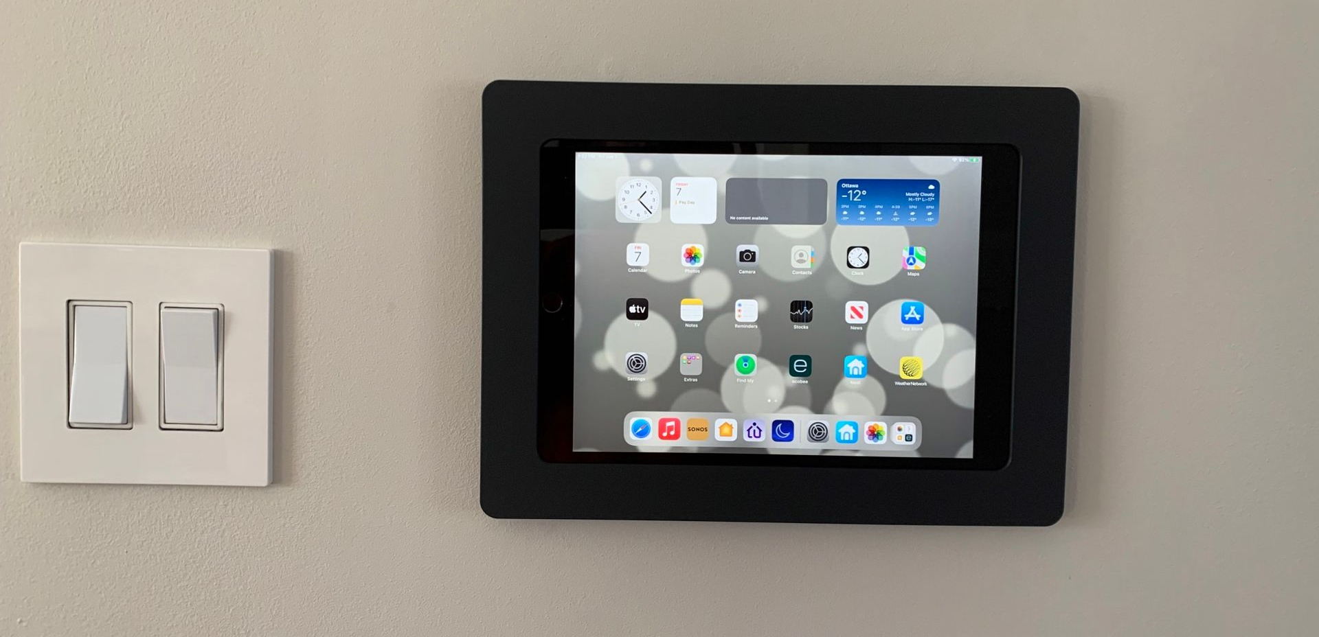 black-framed iPad mounted on light-colored wall