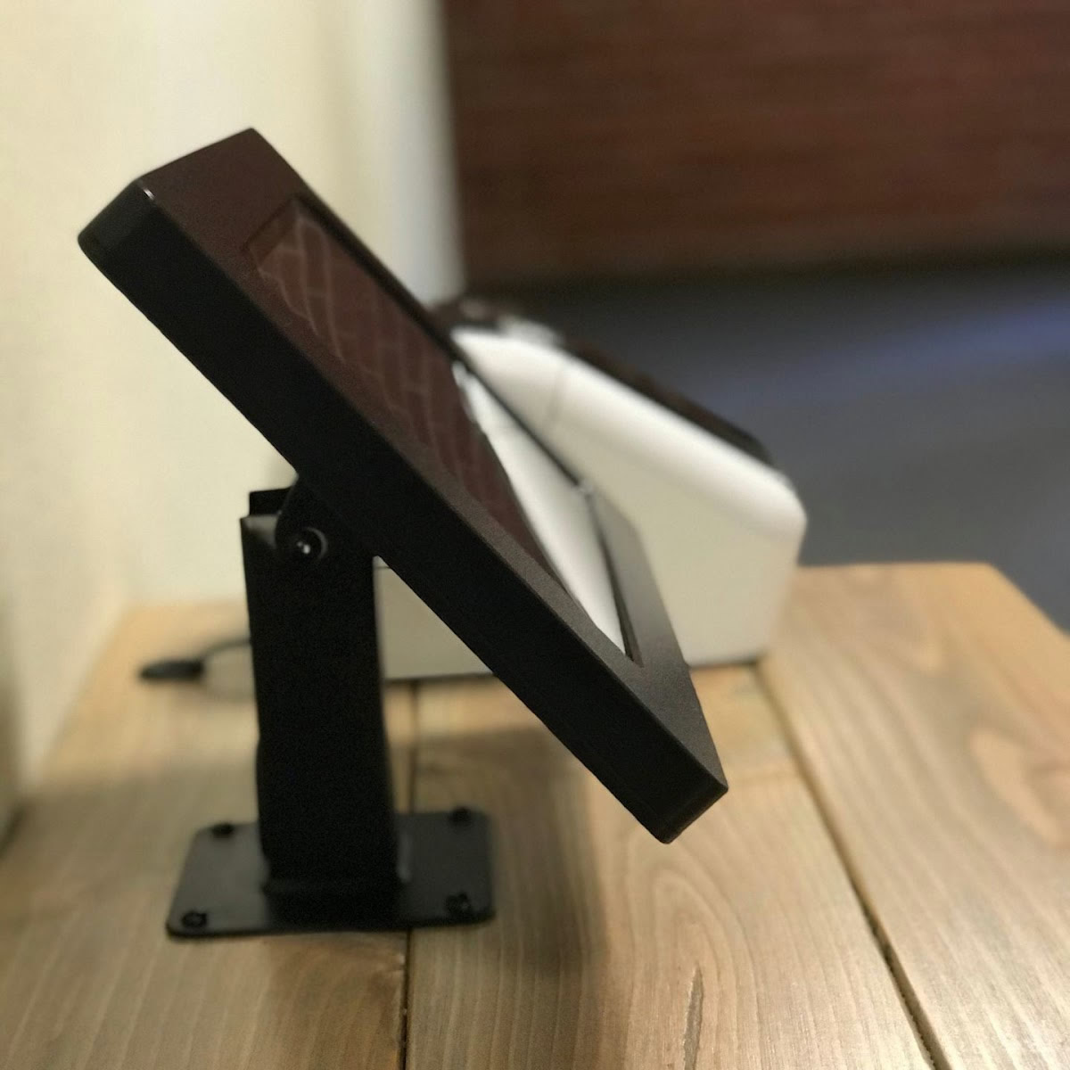 side view of a black tablet stand on wood surface